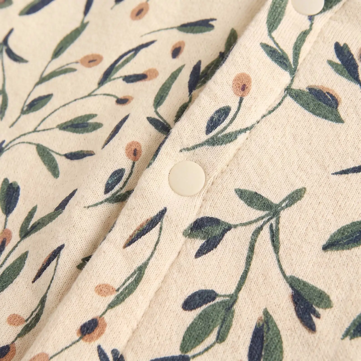 Cream button fastening surrounded by green and blue botanical print on cotton fabric.