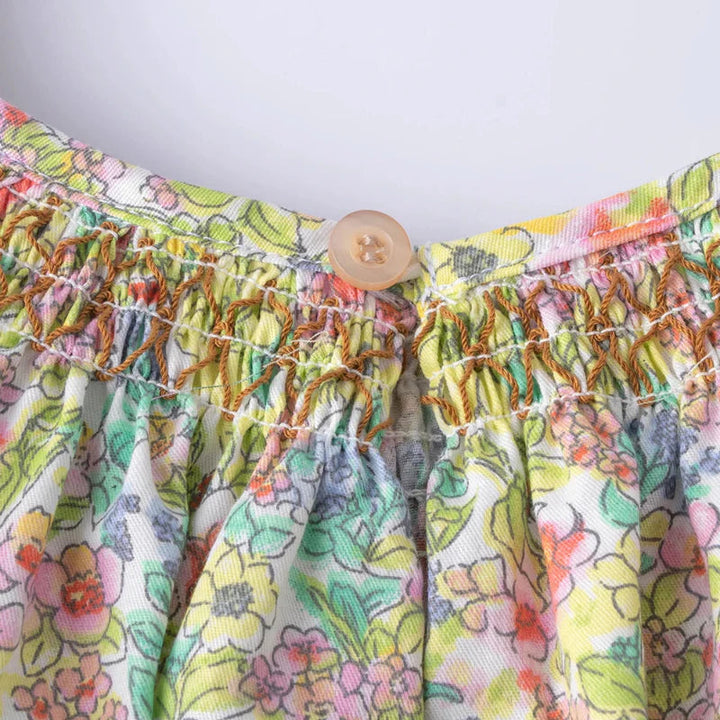 Close-up of the back button closure above the smocked bodice on the floral dress.