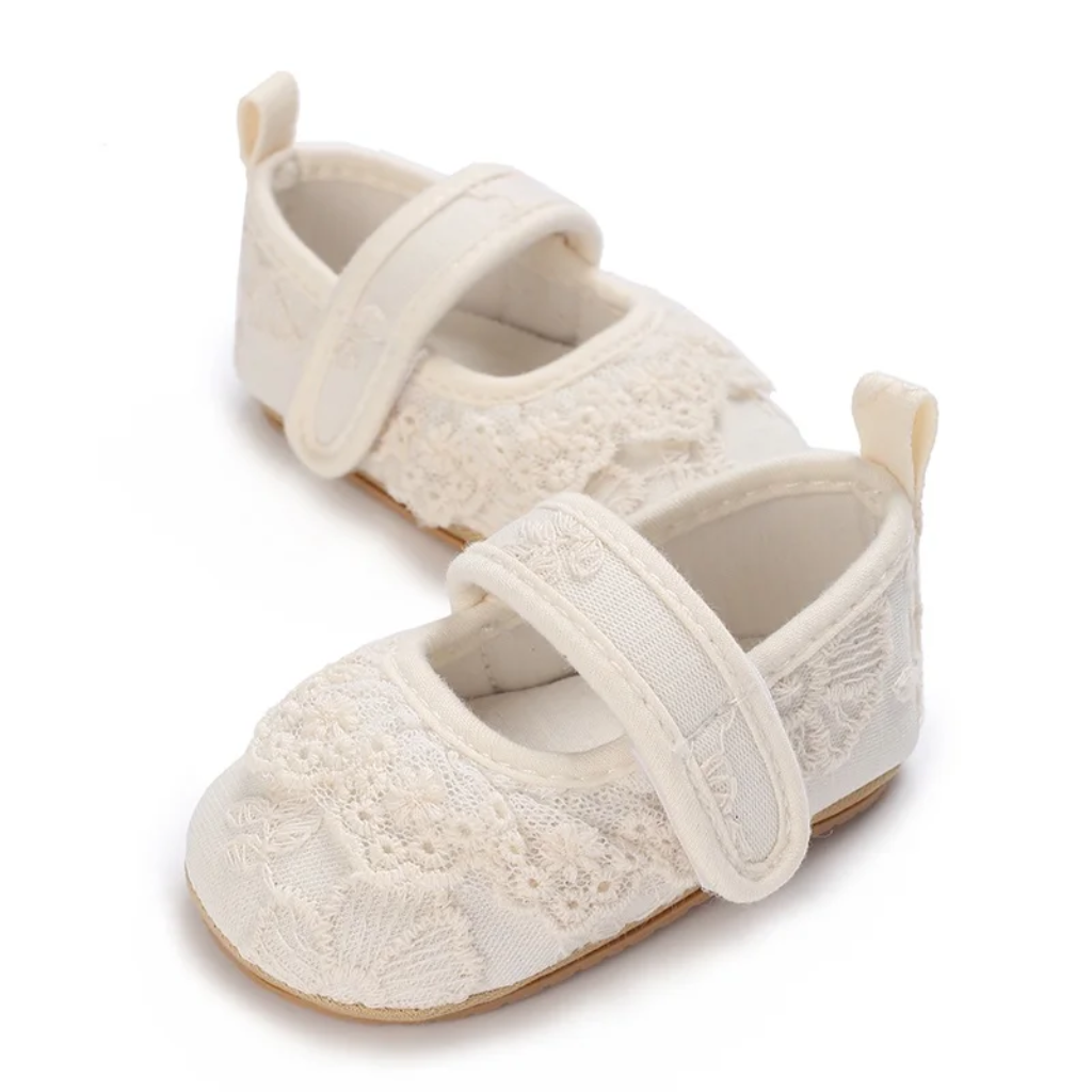 Pair of white floral lace baby shoes shown at an angle