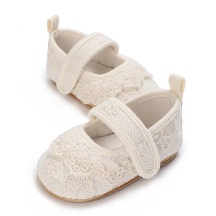 Pair of white floral lace baby shoes shown at an angle