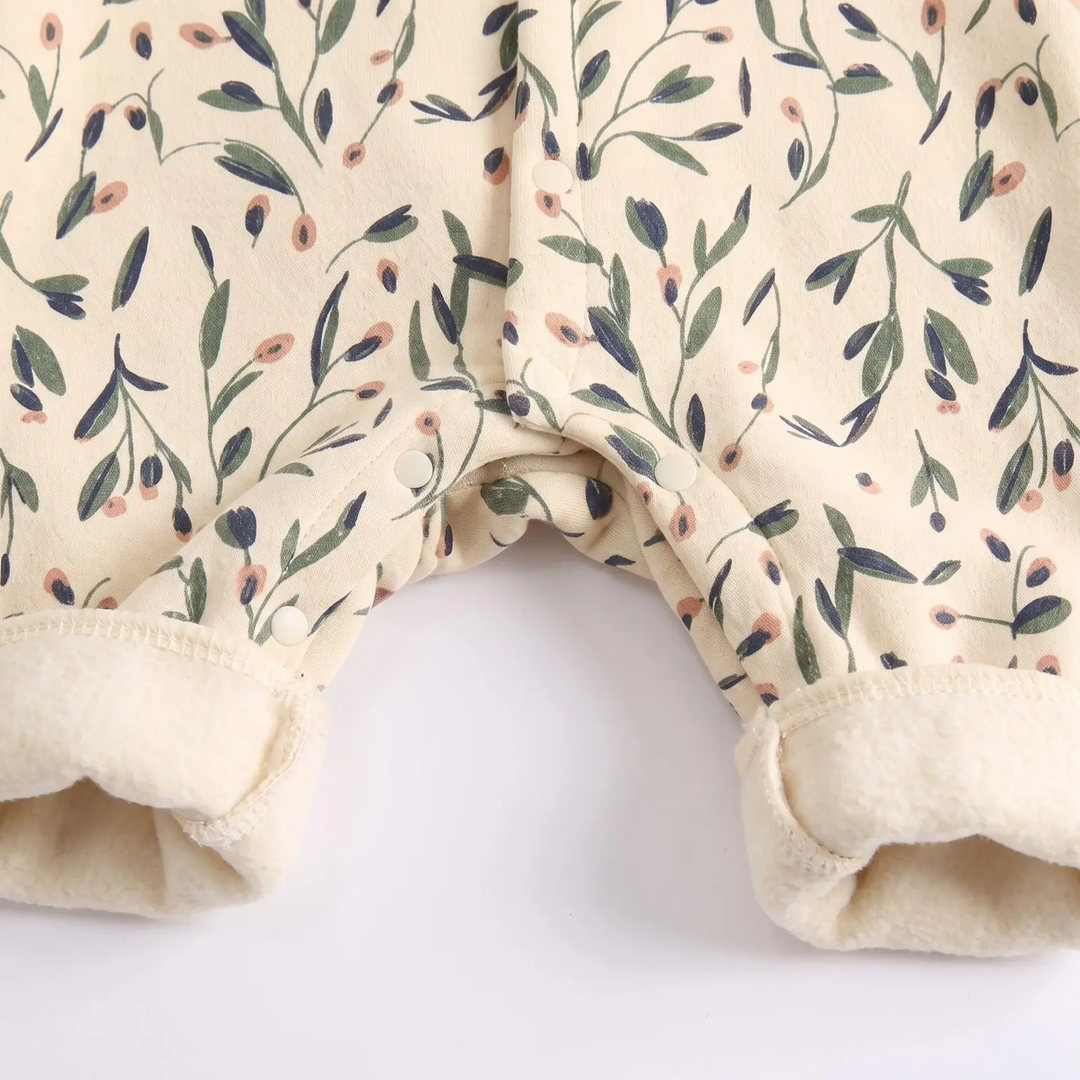Lower button closures and cream ankle cuffs on the floral baby romper.