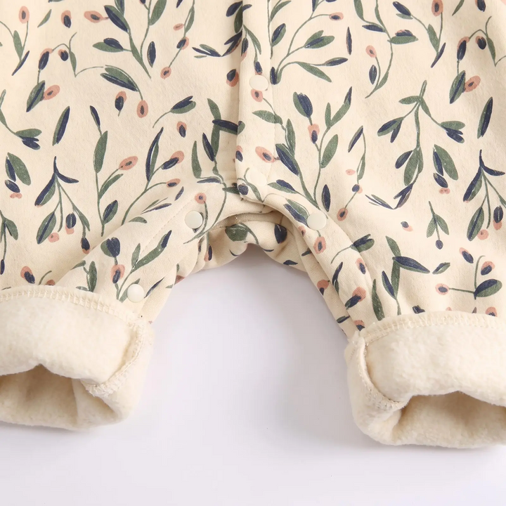 Lower button closures and cream ankle cuffs on the floral baby romper.