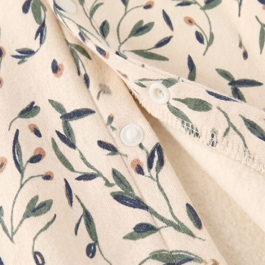 Opened lower fastening showing the cream interior and floral fabric of the baby romper.