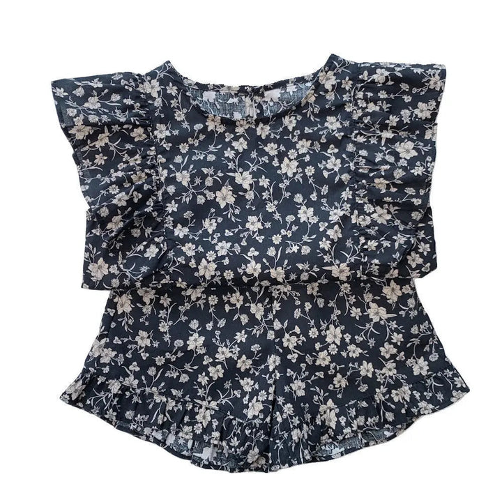 Black floral two-piece outfit laid flat, showing the ruffled top and matching shorts