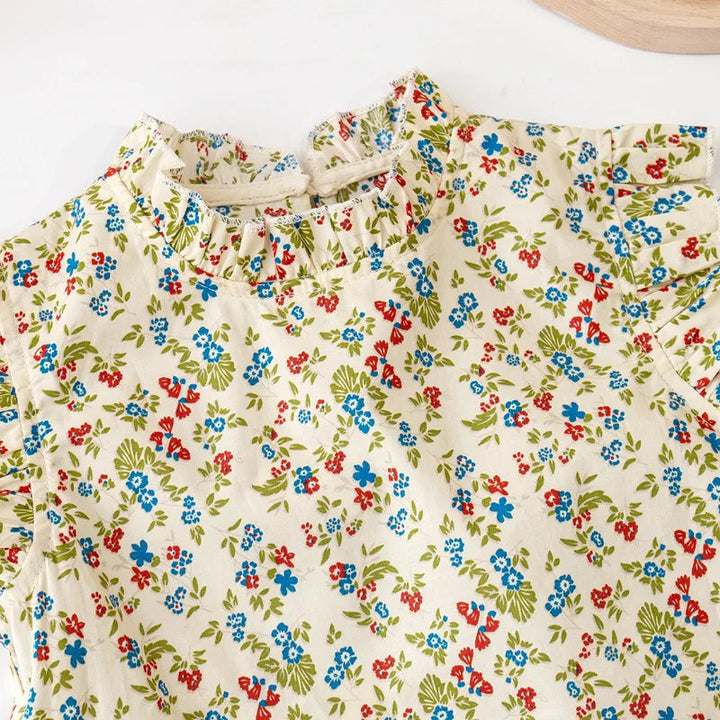 Close-up of the red and blue floral print and ruffled round neckline