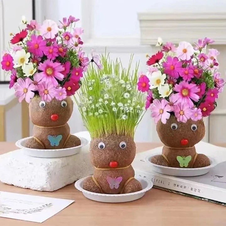 Three flowering plant figures in shallow bowls on a desk beside books