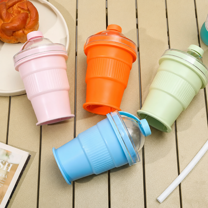 Blue, green, orange, and pink foldable silicone cups with clear domed lids on an outdoor table