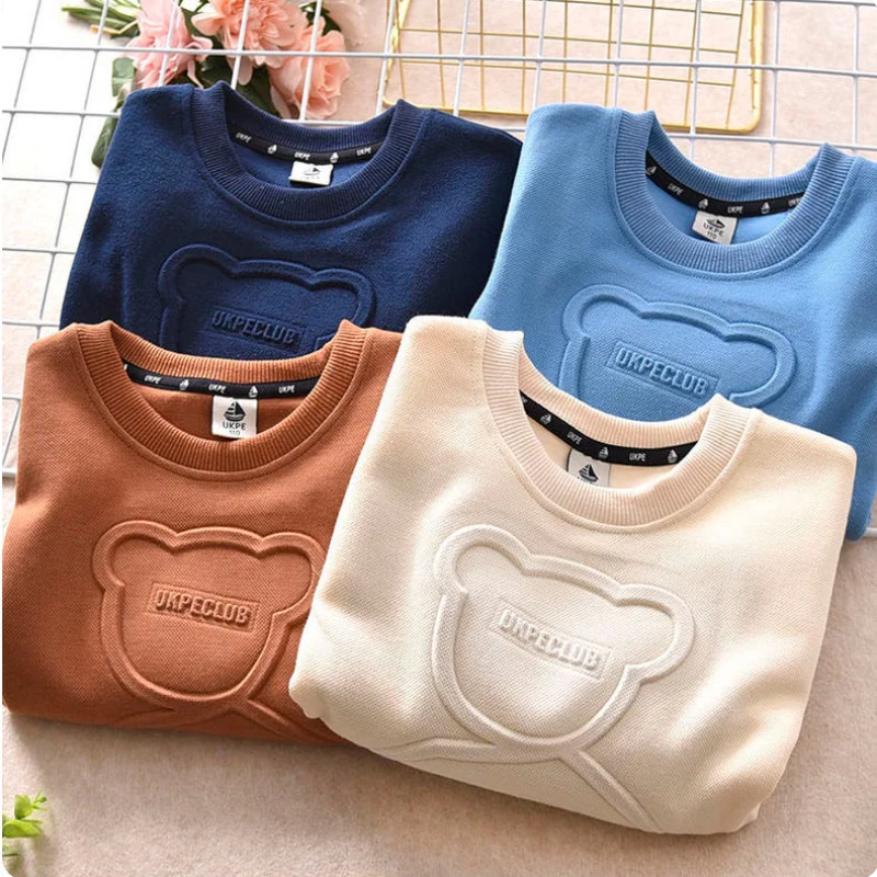 Folded navy blue, blue, brown and apricot sweatshirts showing raised bear details