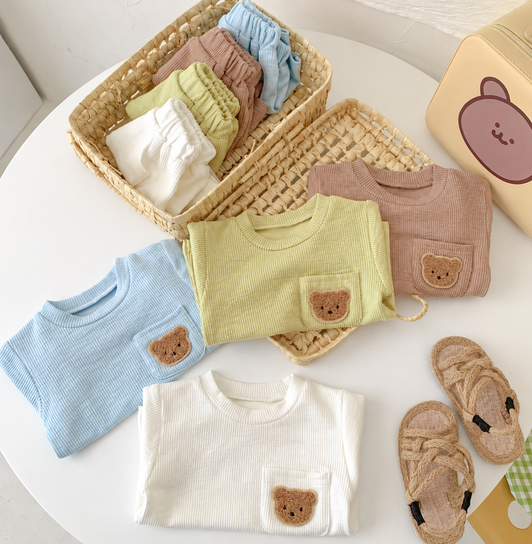 Folded bear-pocket tops beside a basket of matching shorts
