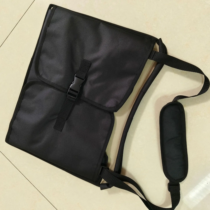 Folded black travel tray with a buckle closure and padded carrying strap