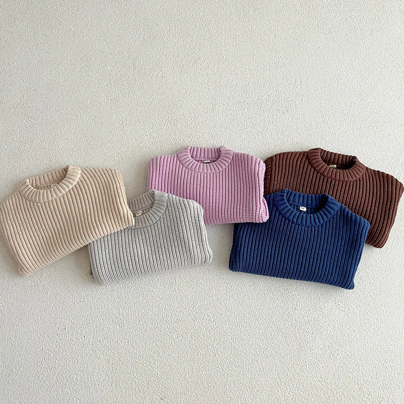 Five folded crewneck sweaters in apricot, gray, purple, dark blue, and brown.