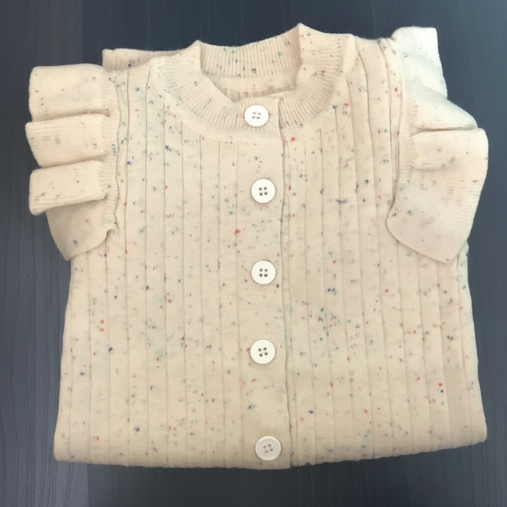 Folded beige knit baby romper showing front buttons, shoulder ruffles, and tiny color flecks