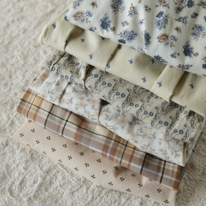 Folded fabrics showing blue floral, small-print, and beige checkered patterns.