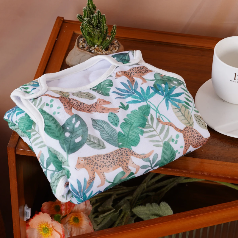 Folded jungle-print baby sleep sack resting on a wooden table