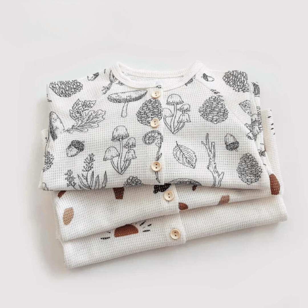 Stack of folded printed cotton pajama tops with round necklines and button fronts
