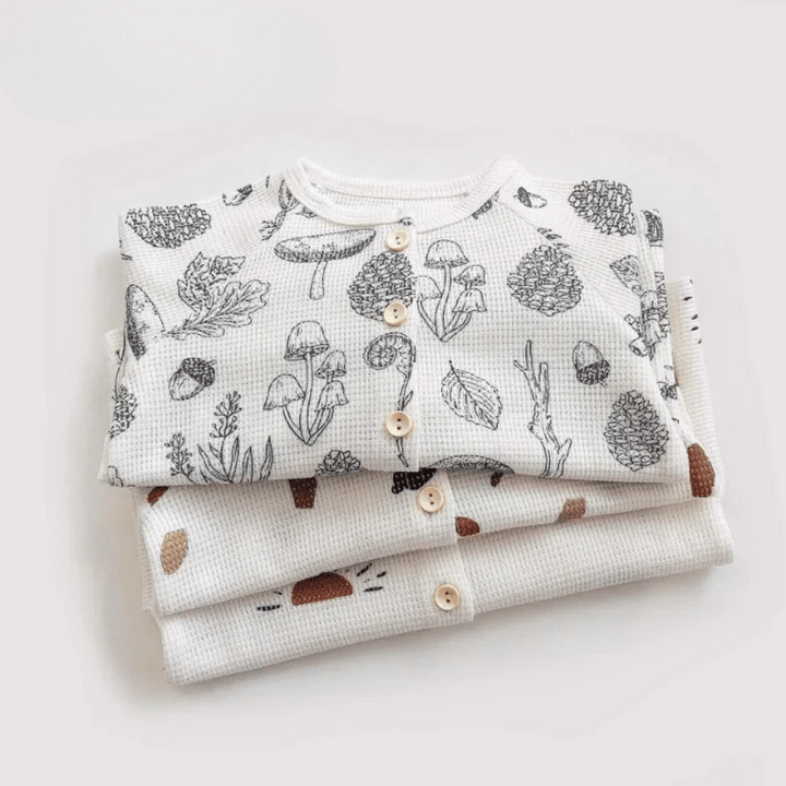 Stack of folded printed cotton pajama tops with round necklines and button fronts