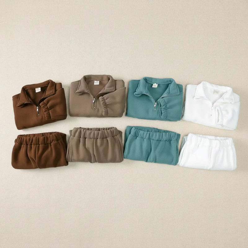 Four folded sweatshirt and jogger sets arranged in brown, taupe, green, and white