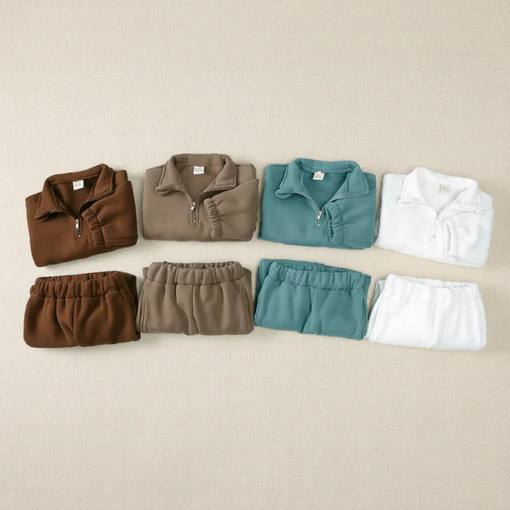 Four folded sweatshirt and jogger sets arranged in brown, taupe, green, and white
