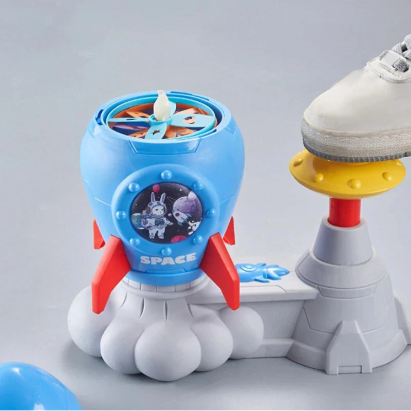 A shoe pressing the yellow pedal on a blue rocket launcher loaded with colorful discs