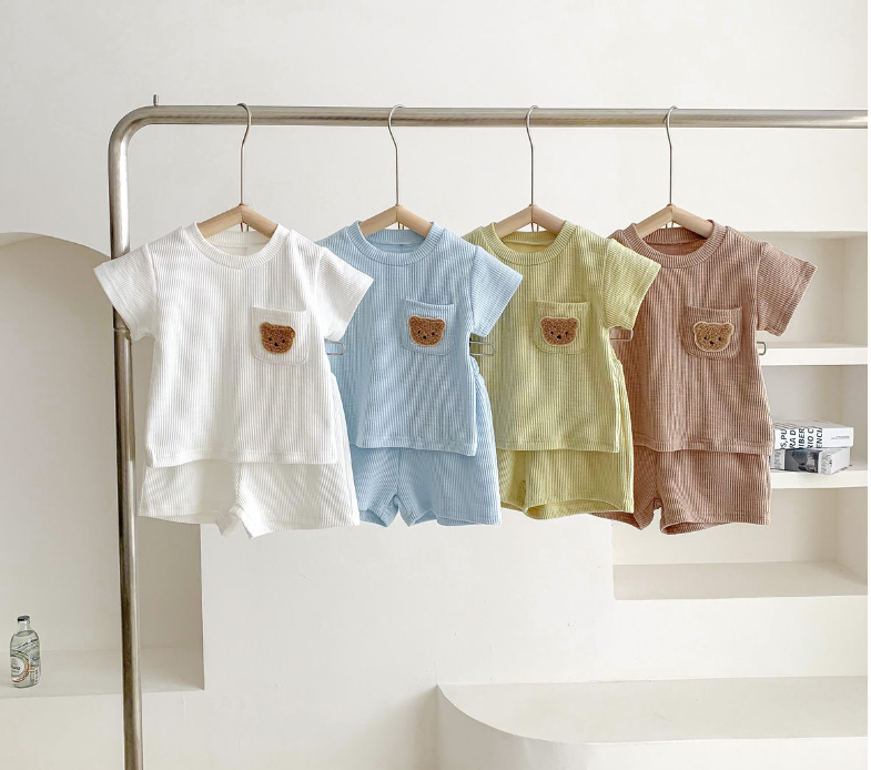 White, blue, green, and brown bear-pocket outfits hanging on a rail