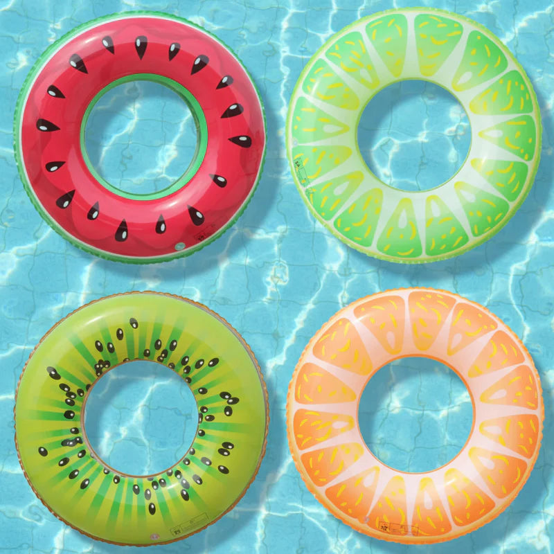 Watermelon, lime, kiwi, and orange swim rings floating in a pool.