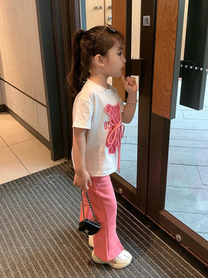Side view of the white short-sleeve bear T-shirt and pink flared pants
