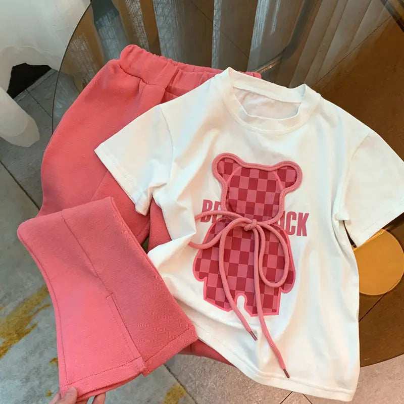 White checker-bear T-shirt and pink flared pants laid out together