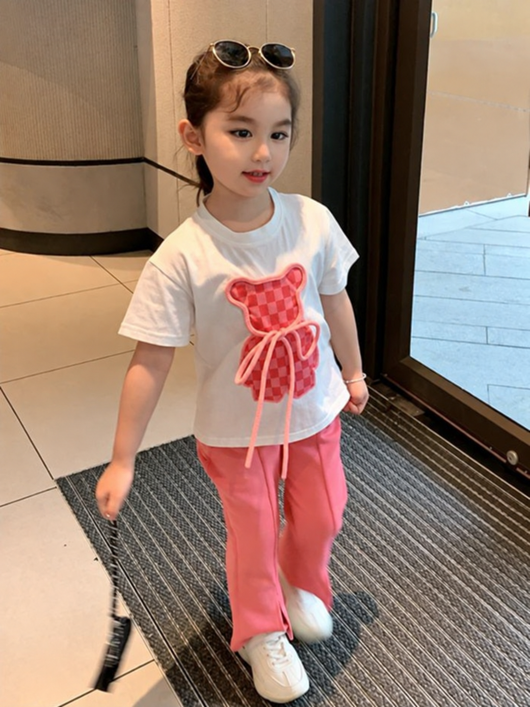 Front view of a girl wearing the white bear T-shirt and pink flared pants