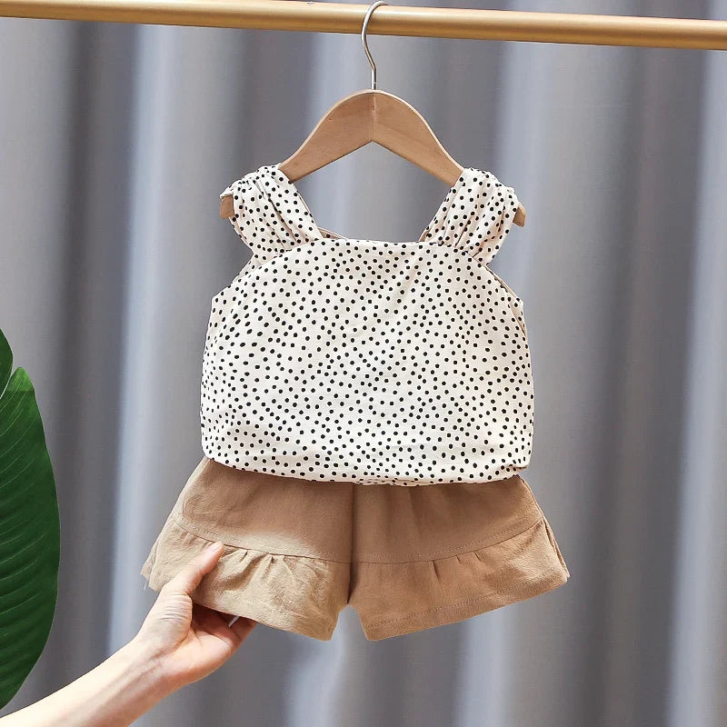 Two-piece summer outfit with a dotted sleeveless top and tan shorts on a hanger