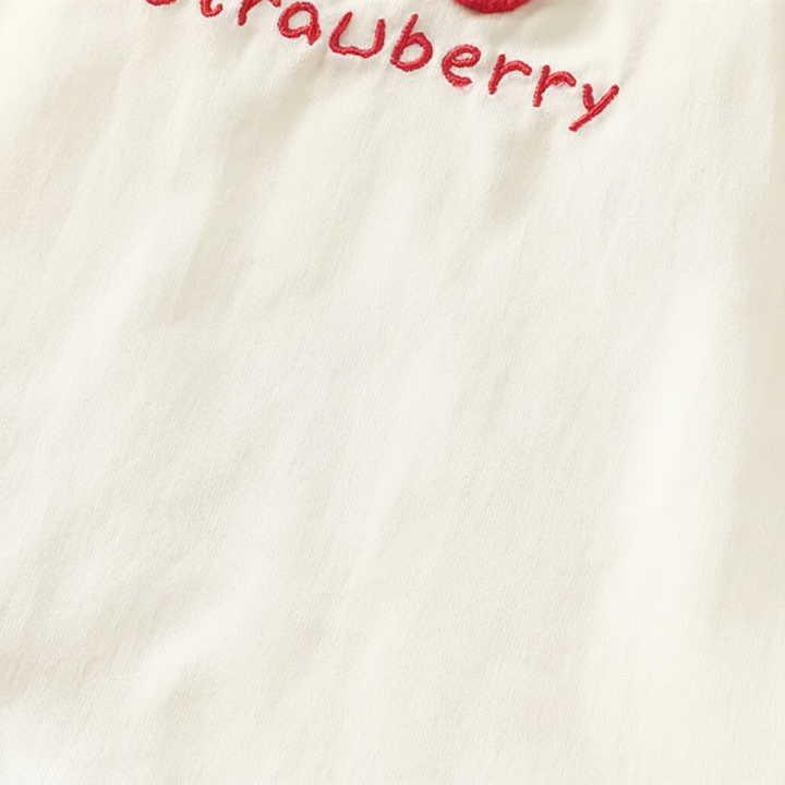 Close-up of the cream dress fabric beneath the red embroidered lettering