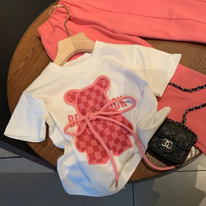 White bear T-shirt on a hanger with coordinating pink pants laid behind it