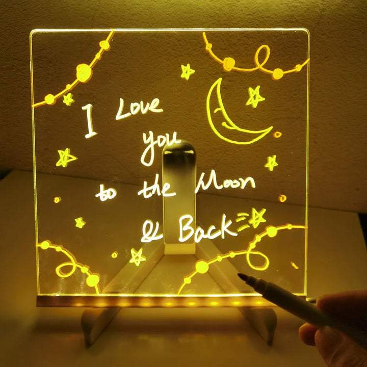 Illuminated drawing board with a handwritten message, moon, and stars on a tabletop stand