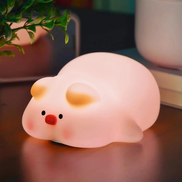 Pink pig night light glowing on a wooden tabletop