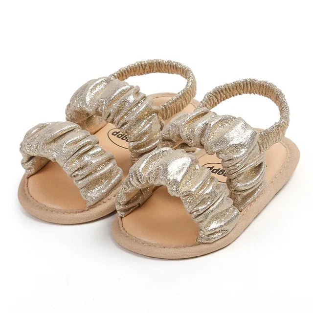 Gold baby sandals with shimmering gathered straps and elastic heel straps