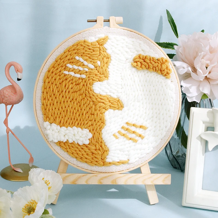 Golden cat silhouette punch needle hoop on white fabric, displayed on a small wooden easel