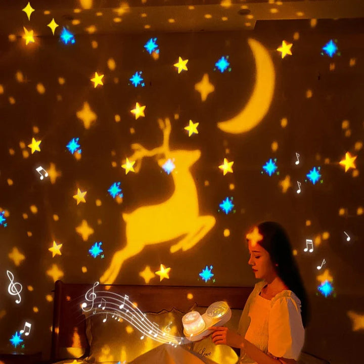 A woman beside a night light casting golden deer, moon, and star shapes on a bedroom wall.