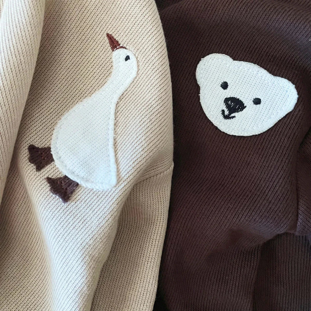 Close-up of the goose and bear chest details on beige and brown cotton fabric