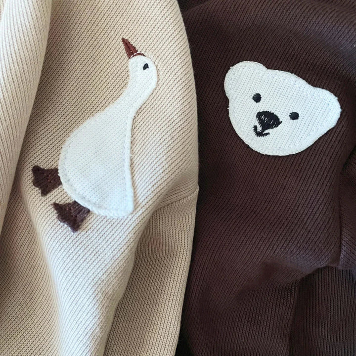Close-up of the goose and bear chest details on beige and brown cotton fabric