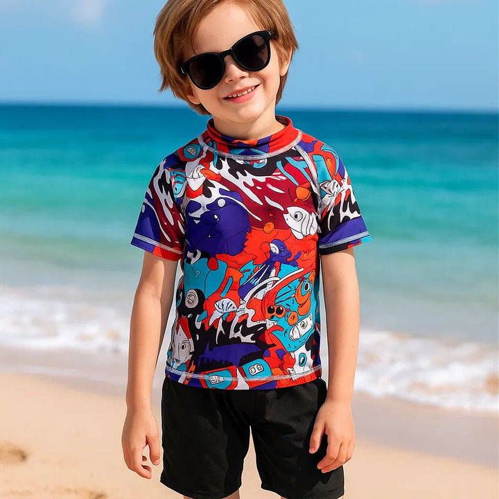 Child wearing a colorful graffiti-print swim shirt on the beach