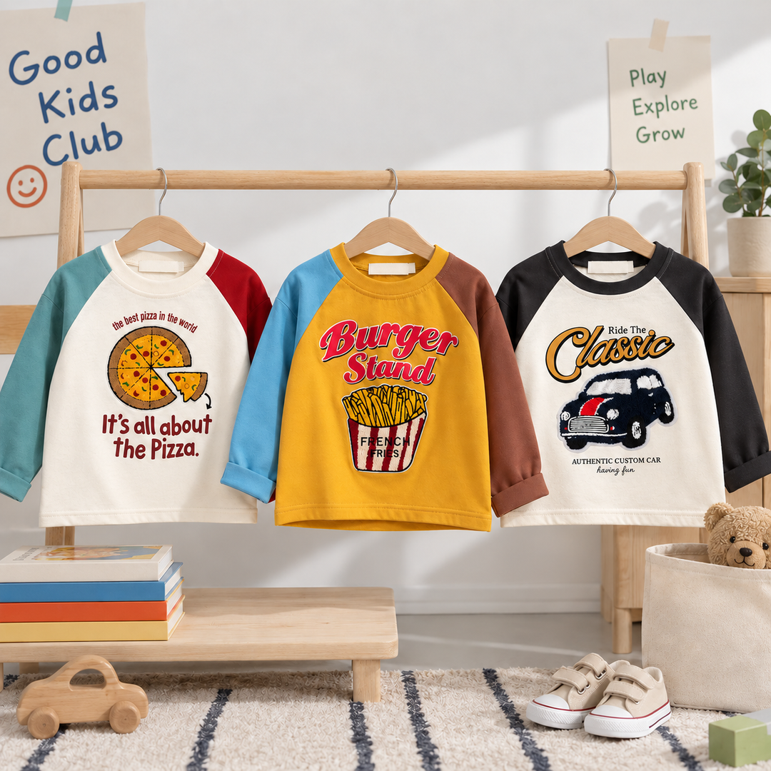 Three kids' graphic raglan shirts with pizza, fries and classic car designs hanging on a wooden rack