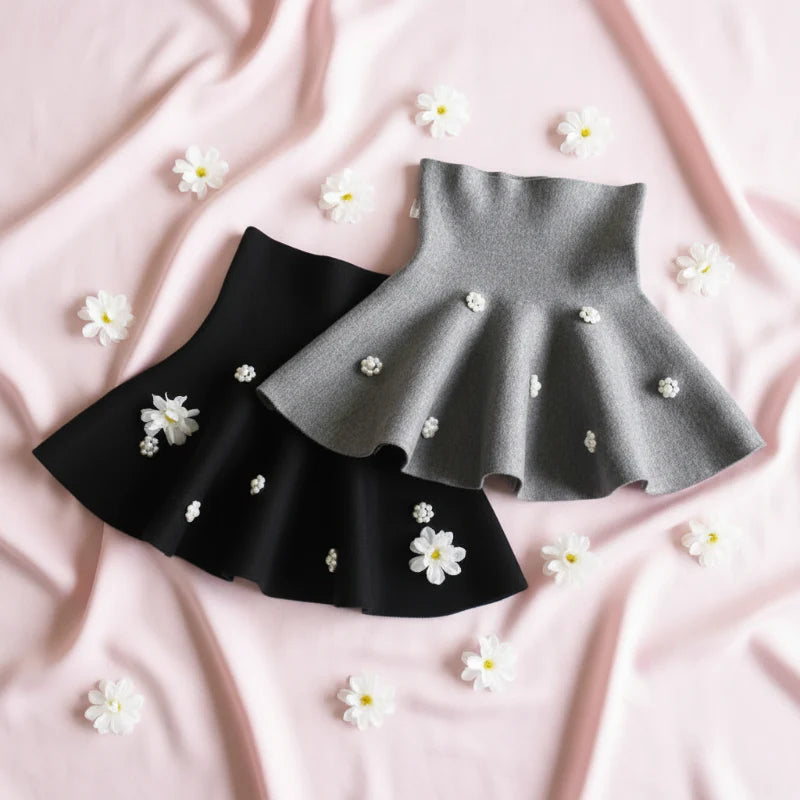 Gray and black knit skirts arranged with small white flowers on pink fabric