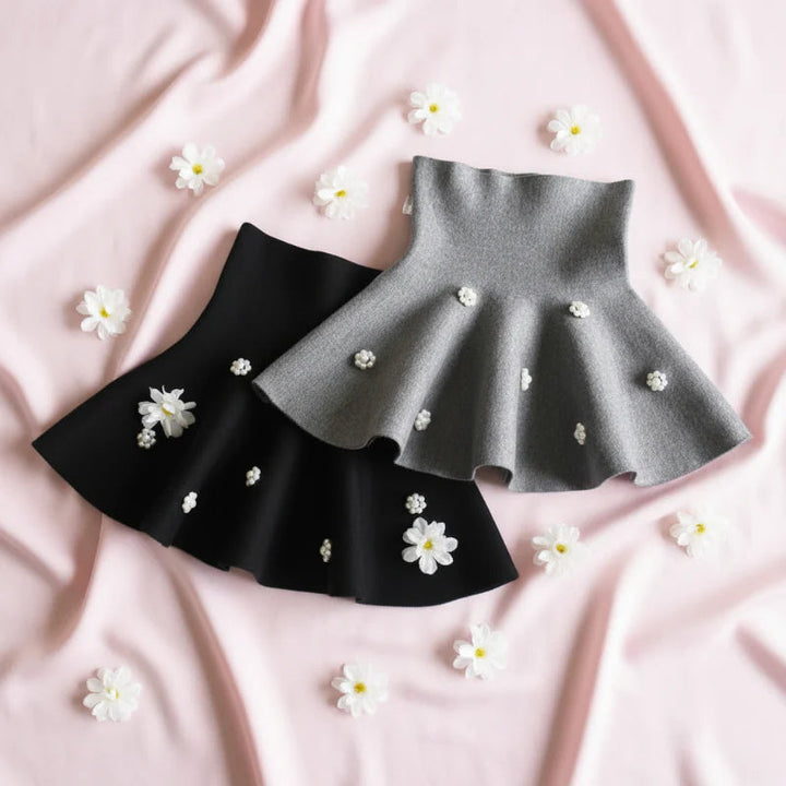 Gray and black knit skirts arranged with small white flowers on pink fabric