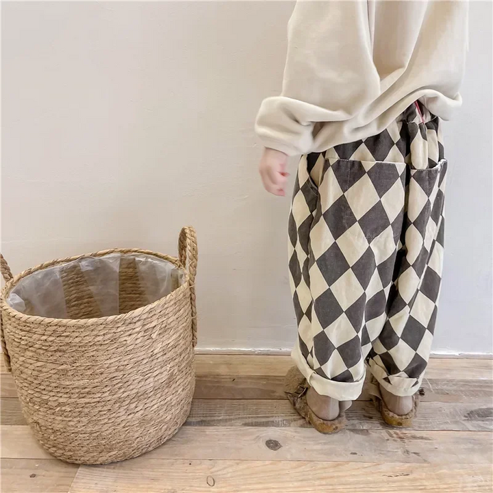 Side view of a child wearing gray argyle pants with a gathered waistband and rolled cuffs