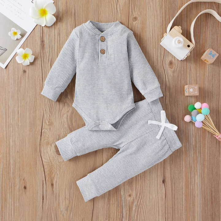 Gray ribbed baby bodysuit and matching pants arranged on a wooden surface