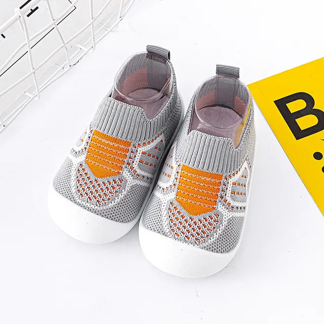 Gray baby slip-on shoes with orange knit accents and heel pull tabs