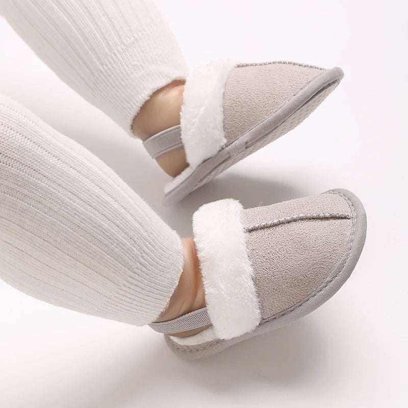 Gray baby slippers with white plush trim worn with ribbed leggings
