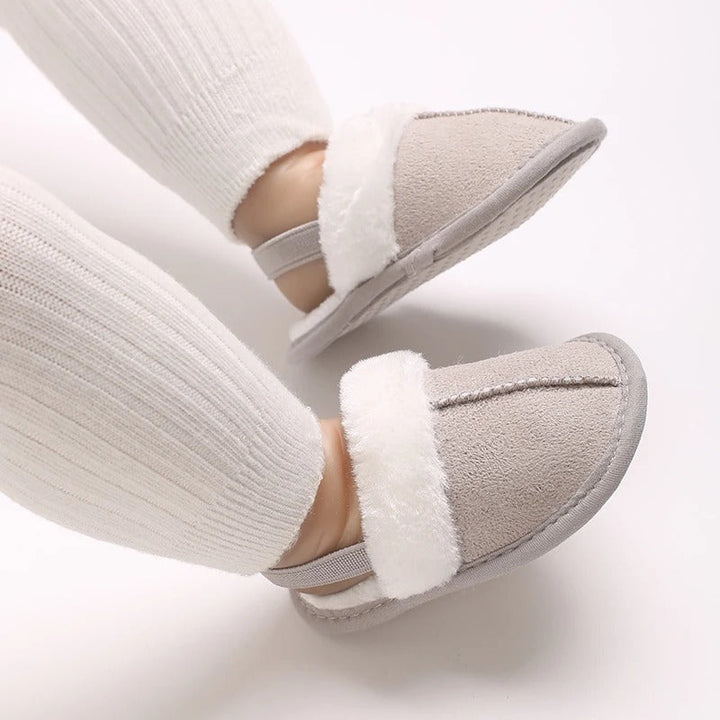 Gray baby slippers with white plush trim worn with ribbed leggings