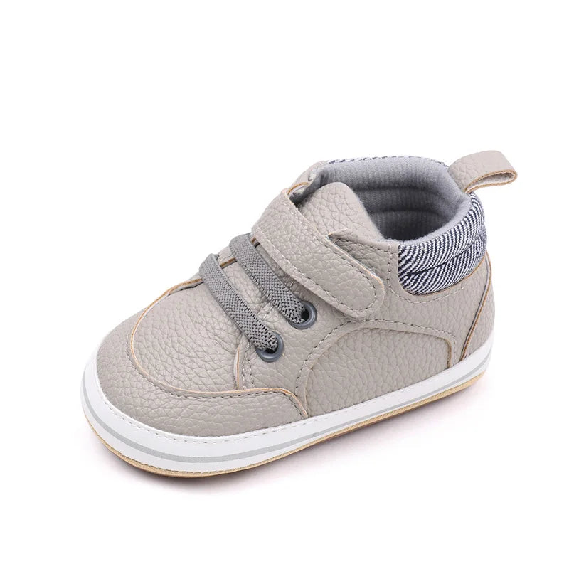 Gray baby sneaker with a hook-and-loop strap, lace detailing, and striped heel collar