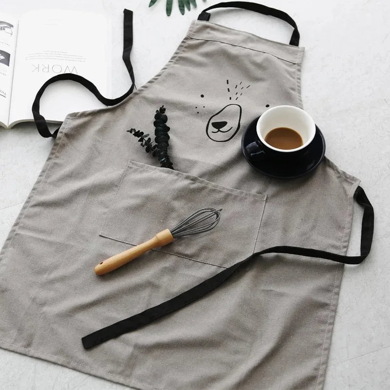 Gray bear apron with a front pocket, black straps, a whisk, and coffee cup