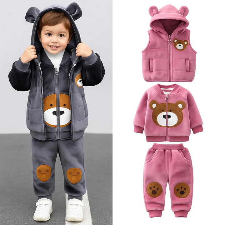 Child wearing a gray bear outfit beside a pink hooded vest, bear-face zip top, and paw-detail pants